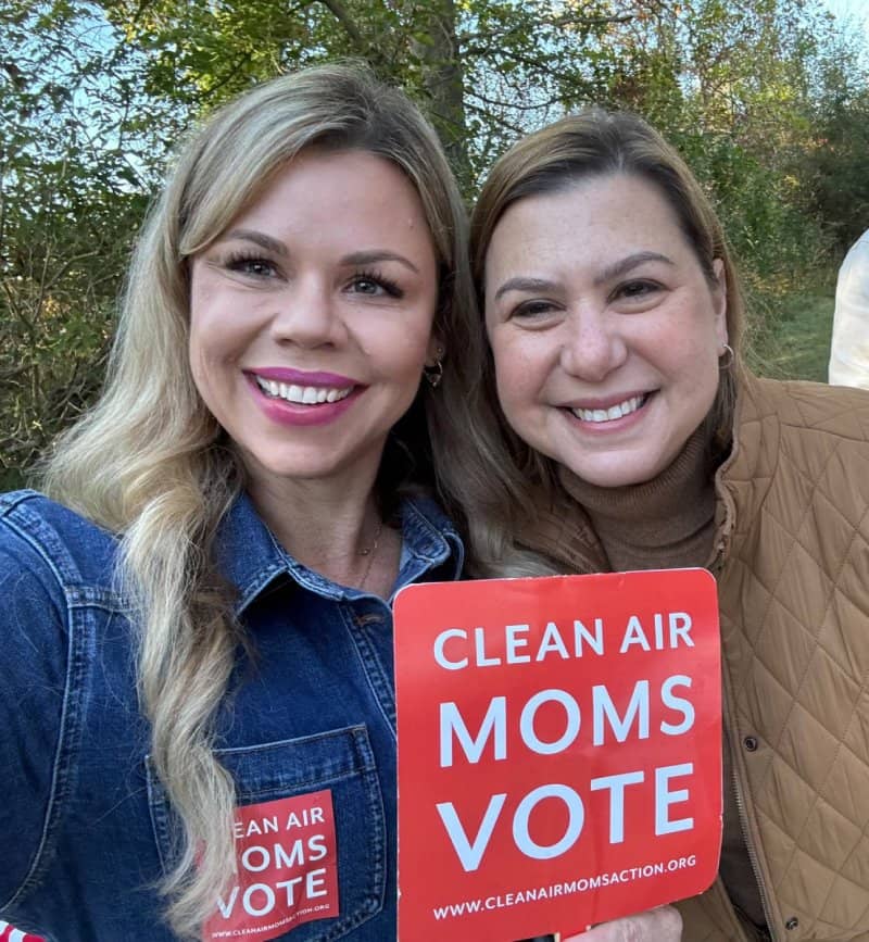 Two women holding a sign that reads "Clean air moms vote"